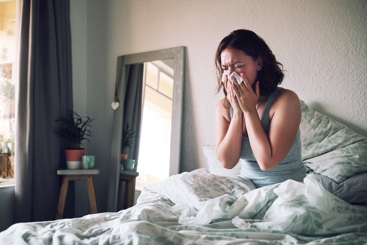 Woman with allergies sneezing in bed