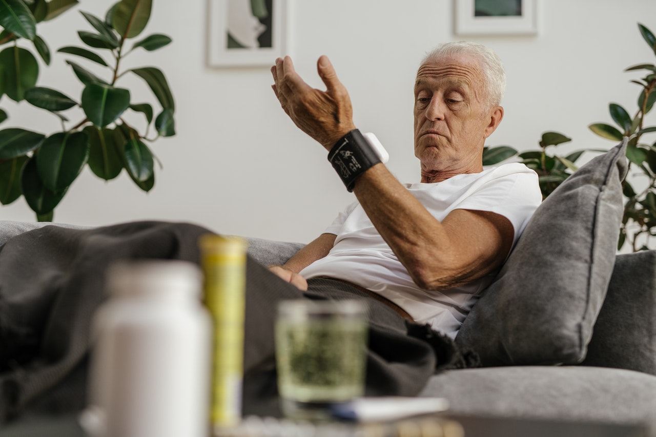 Old man measuring blood pressure on bed