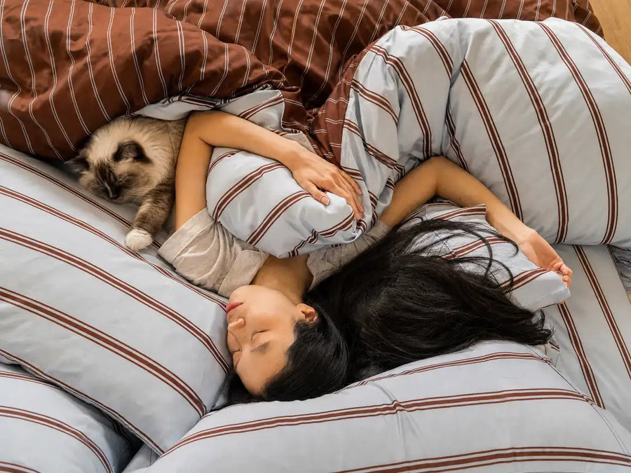 Cat owner asleep with their cat on Ecoy bamboo sheets