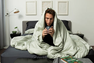 man sipping tea under a sage quilt cover